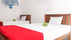 Una habitación de hotel con dos camas, una con una manta roja y la otra con una toalla verde.