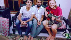 Tres personas sentadas en un sofá con una ventana al fondo.