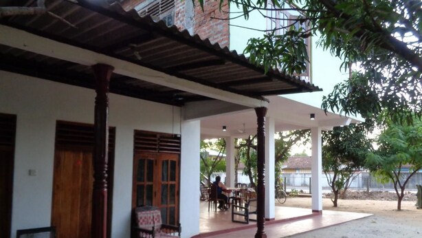 Un espacio al aire libre cubierto con un conjunto de asientos, una puerta de madera y un edificio al fondo.