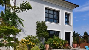 A modern two-story building with large windows and a well-maintained garden with various plants and flowers. - Appart'sHotel Fior Di Ribba (Sartene)