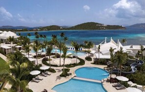 Ein Resort mit großem Pool, Palmen und Blick auf den Ozean.