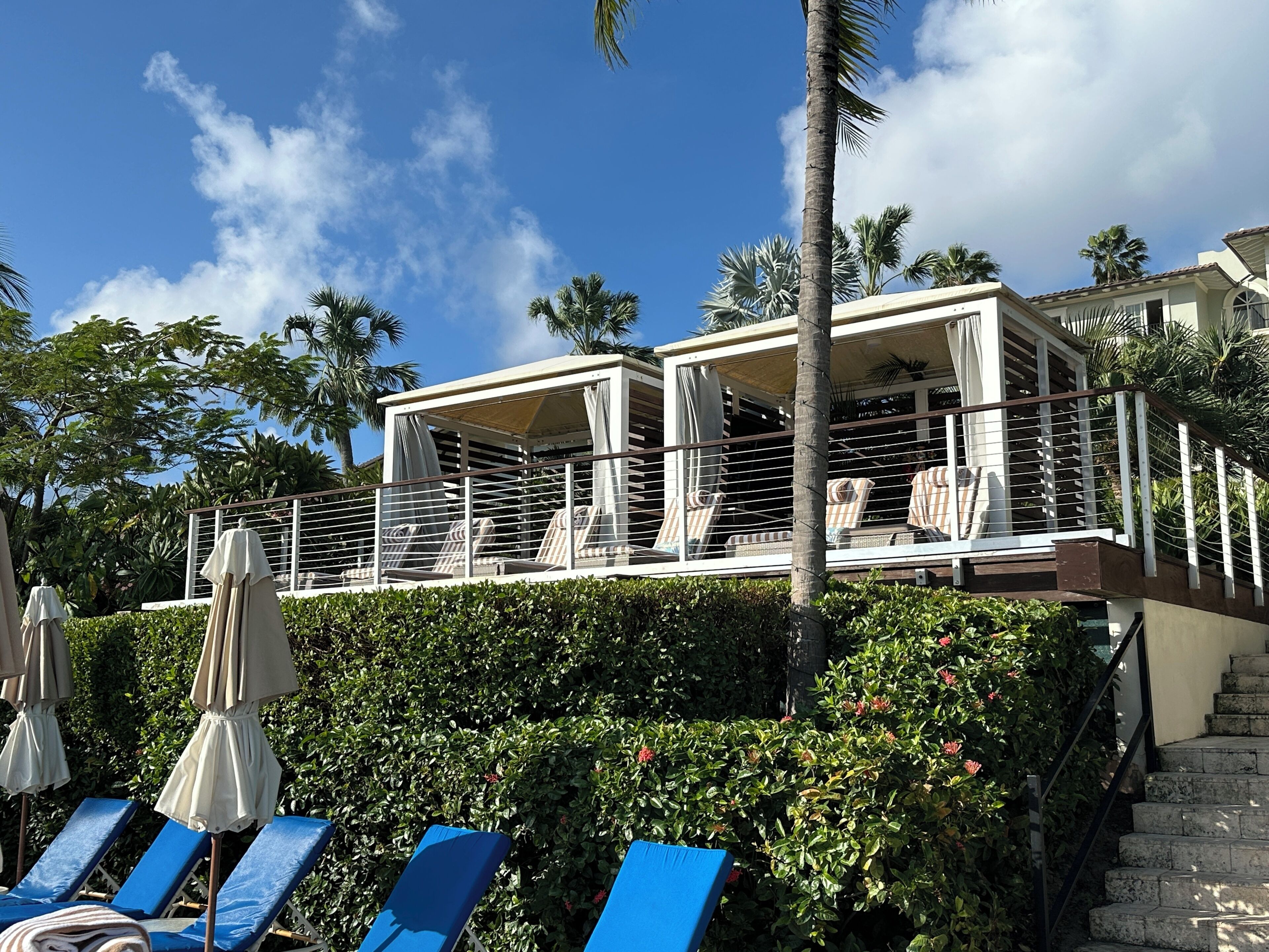 A resort with a pool area, lounge chairs, and a covered seating area with umbrellas.