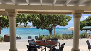 An outdoor patio with a table and chairs, overlooking a clear blue sea. - BEACHFRONT LUXURY at the Ritz! NEWLY RENOVATED - MOST DATES Available! (Nazareth)
