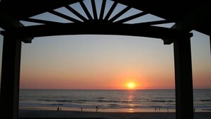 A beach view from a covered area with a sunset. - Oceanfront, Private Beach Access, Newly Updated, Perfect for Family Gatherings! (Lincoln City)