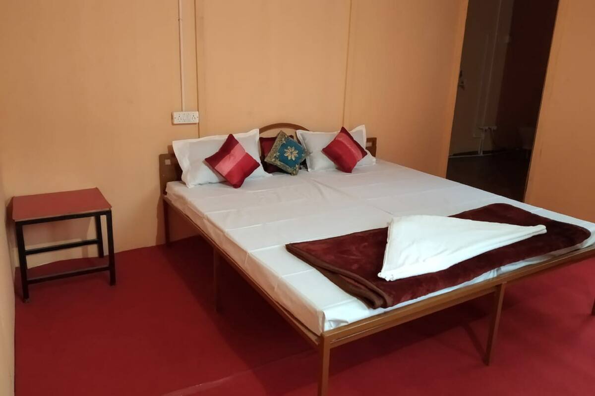 Ein Einzelbett mit Holzbettgestell, weißer Bettwäsche und mehreren Kissen in verschiedenen Farben.