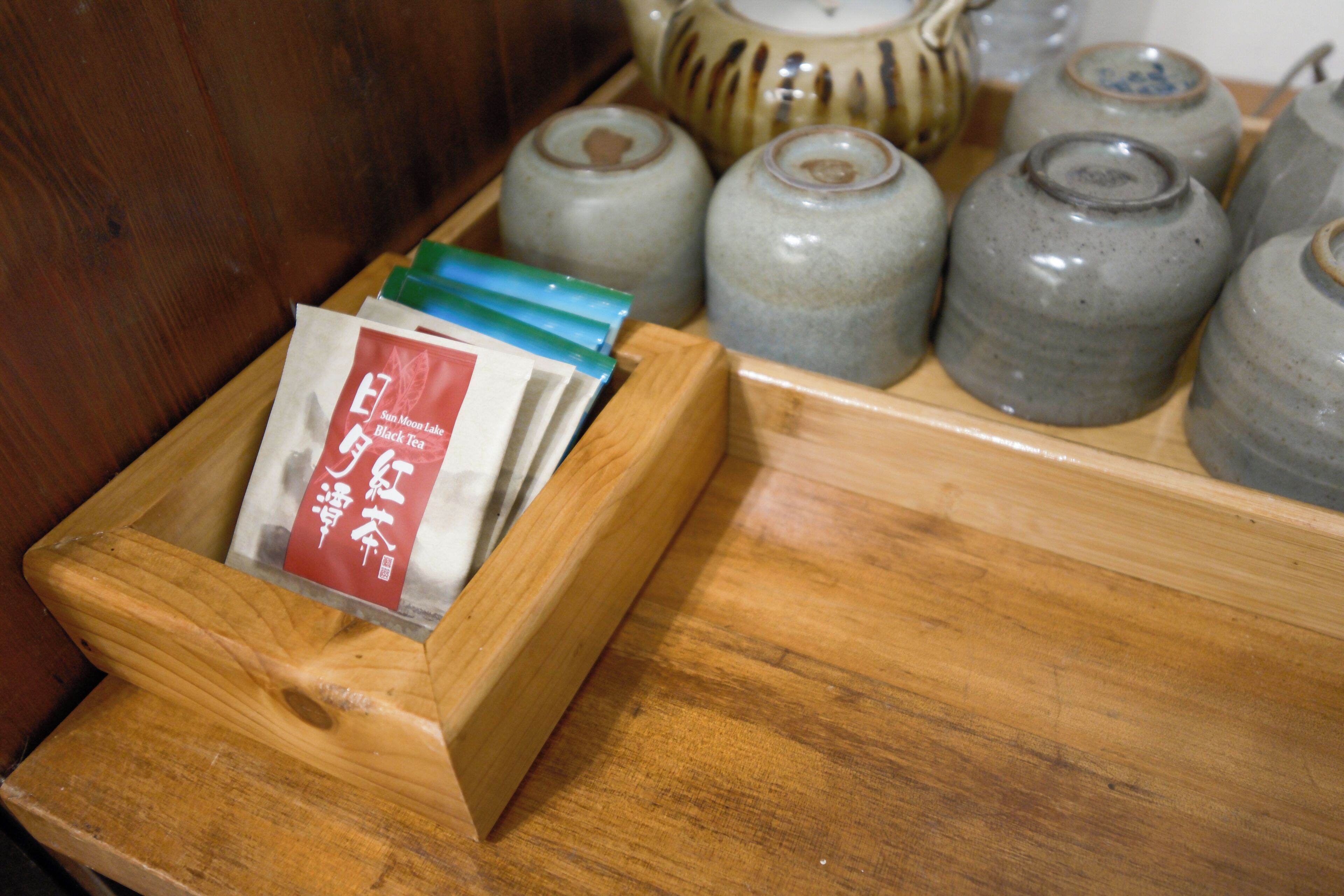 Una bandeja de madera con bolsitas de té y recipientes de cerámica.