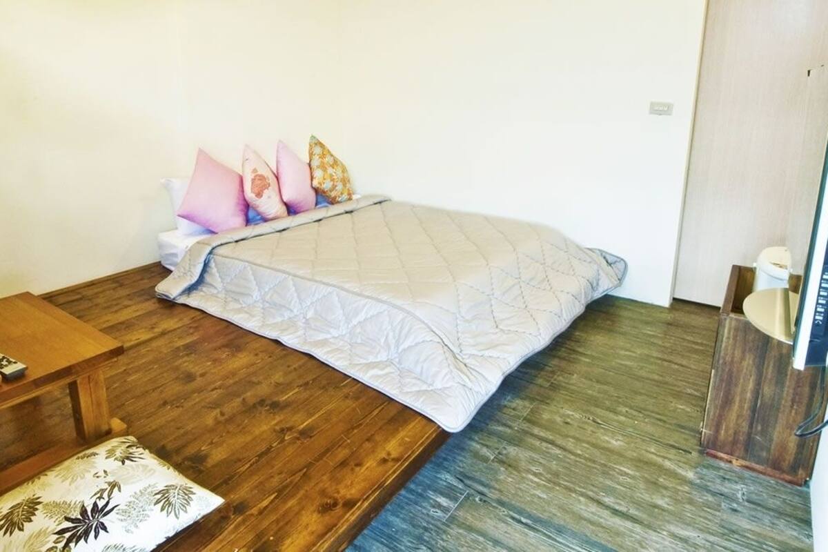 A small, compact room with a bed, a wooden table, and a small bench.