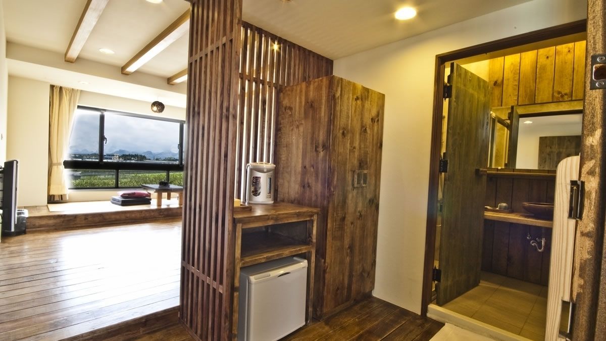 Una habitación moderna con separador de madera, un refrigerador pequeño, cafetera y vistas al exterior.