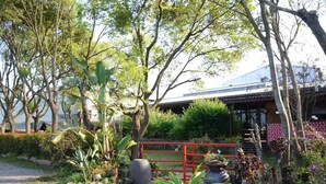 A traditional Japanese-style building with a tiled roof, surrounded by lush greenery and a red gate. - SHYE Lithuania Homestay (Taichung)