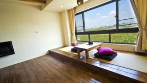 A room with a large window, a wooden floor, a small table, and a cushion. - SHYE Lithuania Homestay (Taichung)