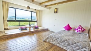 A bedroom with a large window, wooden flooring, a bed with pink pillows, and a view of the outdoors. - SHYE Lithuania Homestay (Taichung)