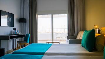 A hotel room with a bed, a desk, a chair, a table, and a balcony with a view.