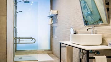 A modern bathroom with a glass shower door, a white sink, and a mirror above it.