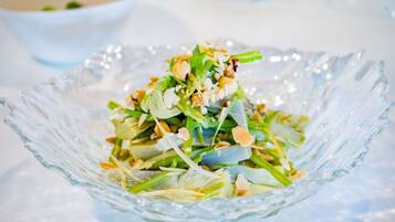 Una ciotola di vetro trasparente con un'insalata di verdure a foglia e noci.