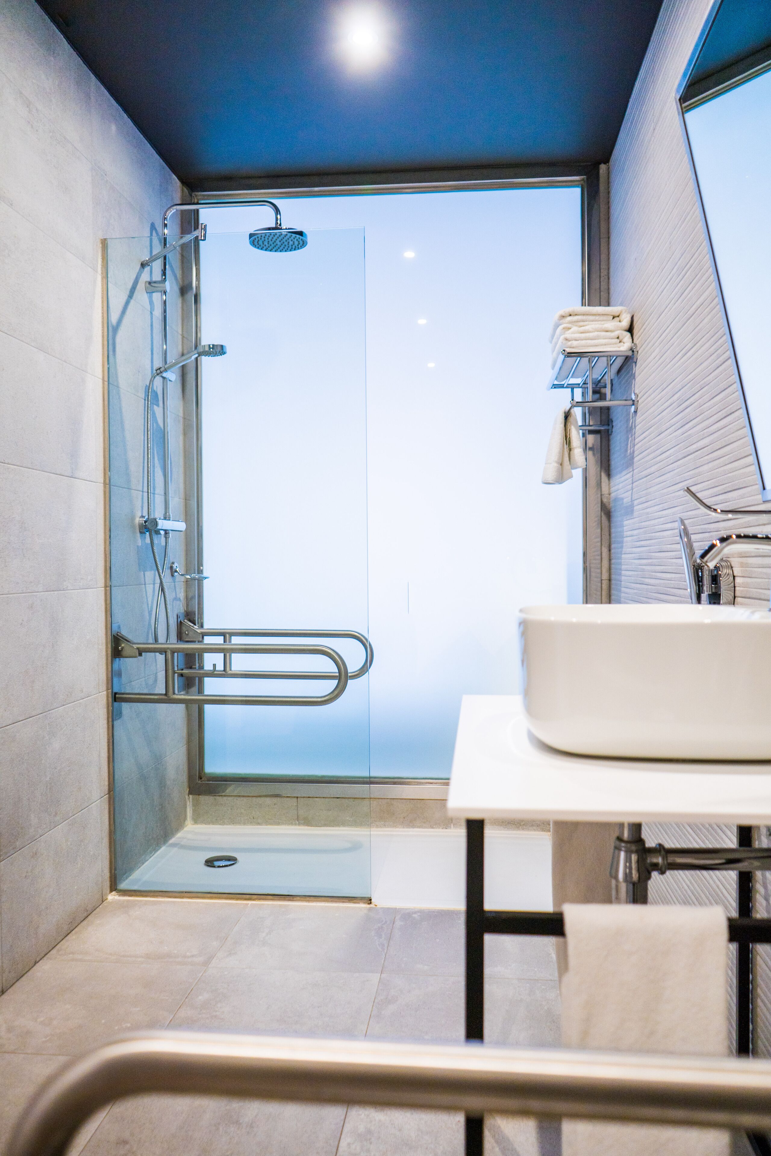 Une salle de bain moderne avec une douche à parois de verre, un lavabo blanc et un porte-serviettes.
