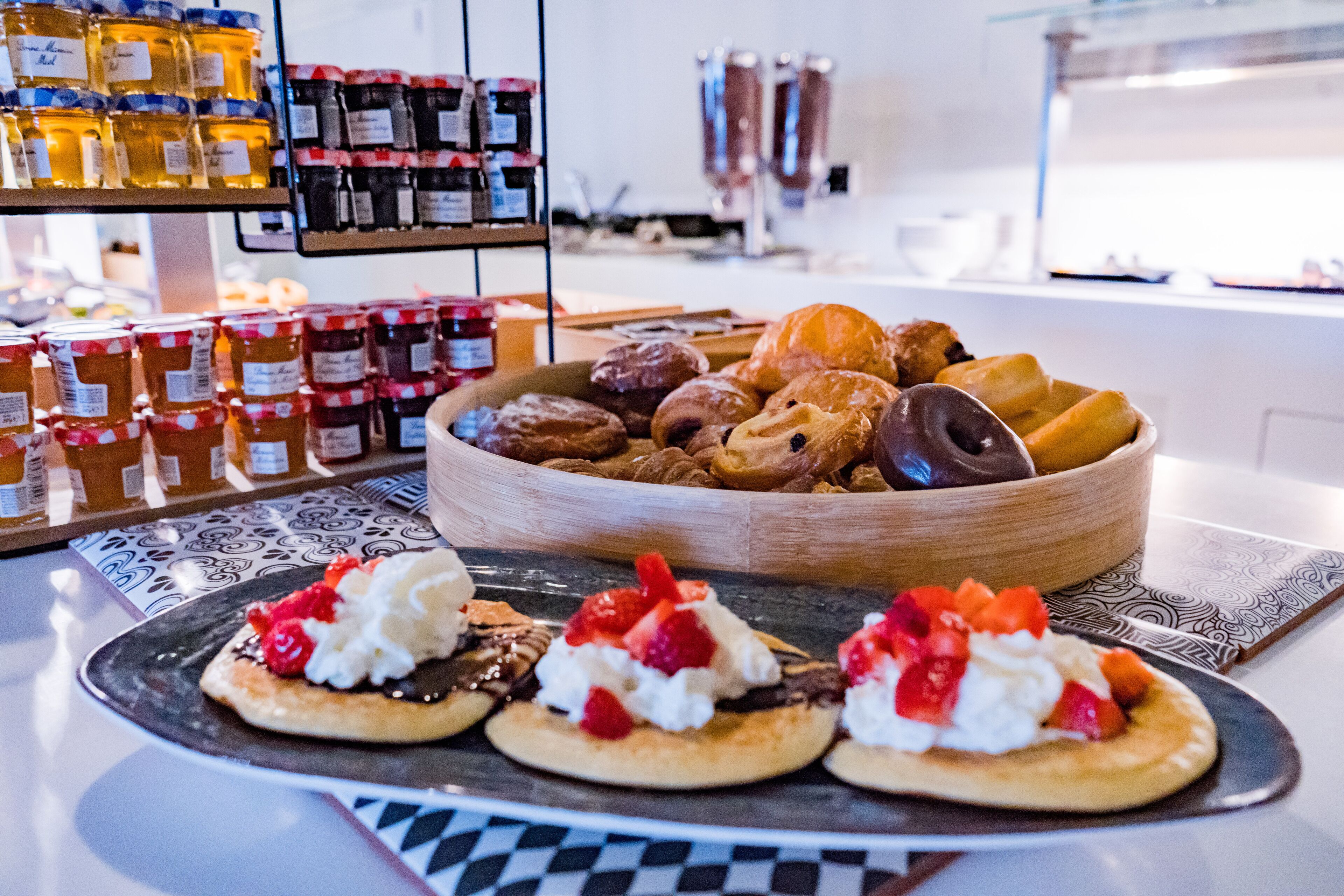 A breakfast buffet with various pastries, jams, and condiments.