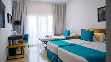 Habitación de hotel con dos camas, un escritorio, una silla y un banco.