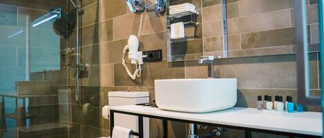 A modern bathroom with a glass-enclosed shower, a white sink, and a mirror above the sink.