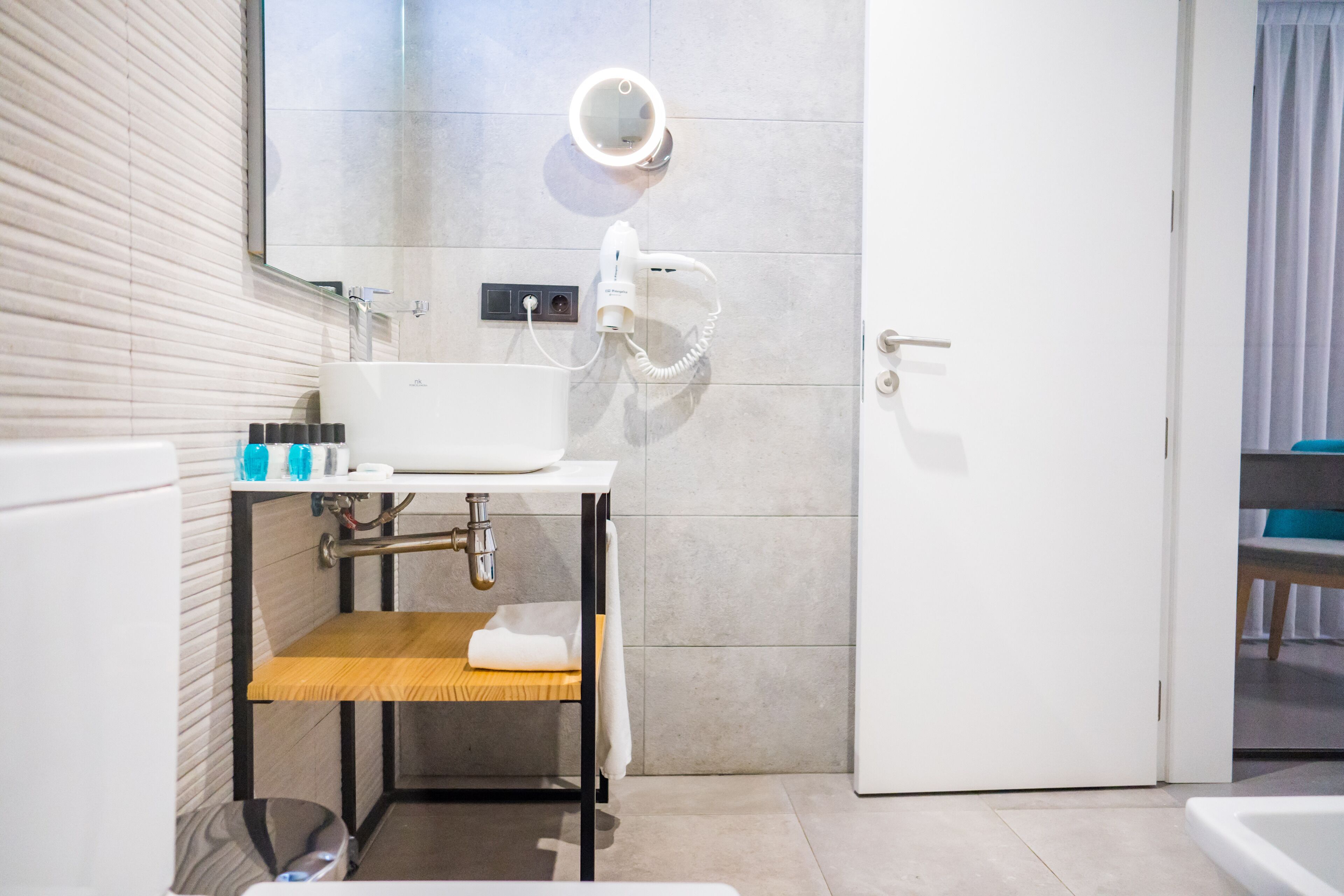 A modern bathroom with a white sink, mirror, and handheld showerhead.