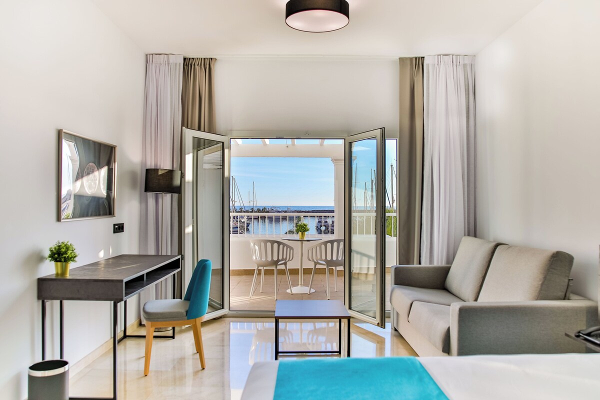Una habitación de hotel moderna con balcón, escritorio, sofá y cama.