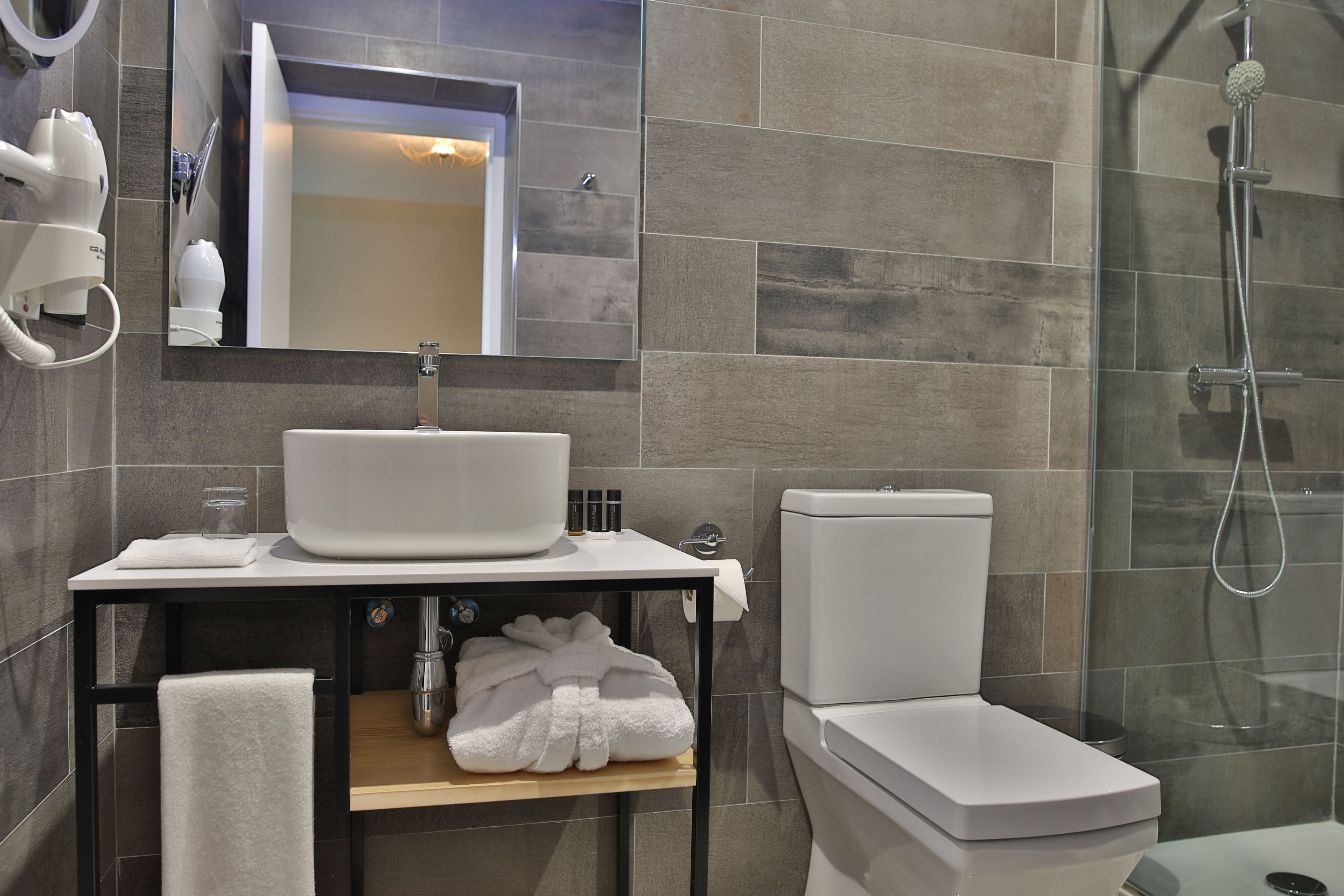 A modern bathroom with a sink, mirror, and toilet.