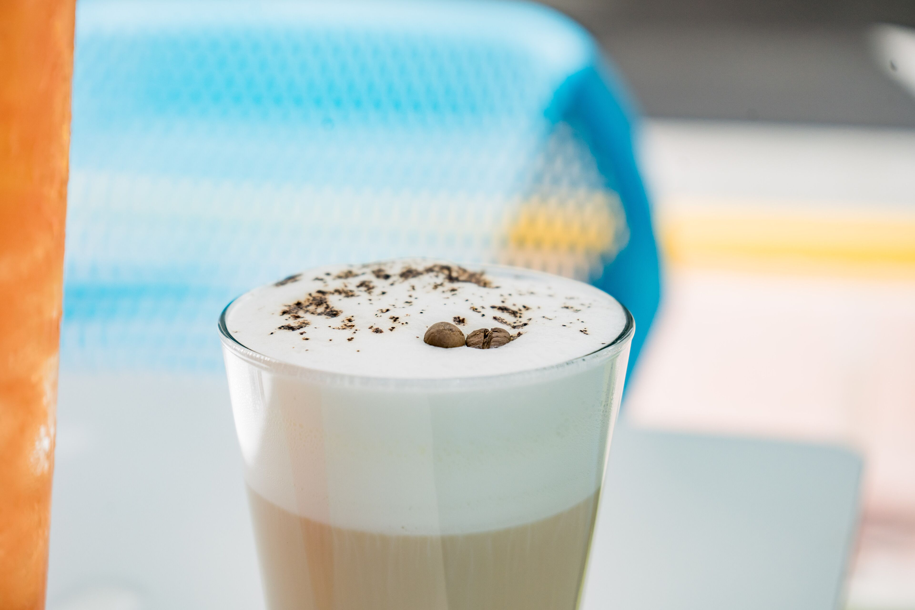 Un vaso de una bebida en capas con una capa cremosa y granos de café encima.