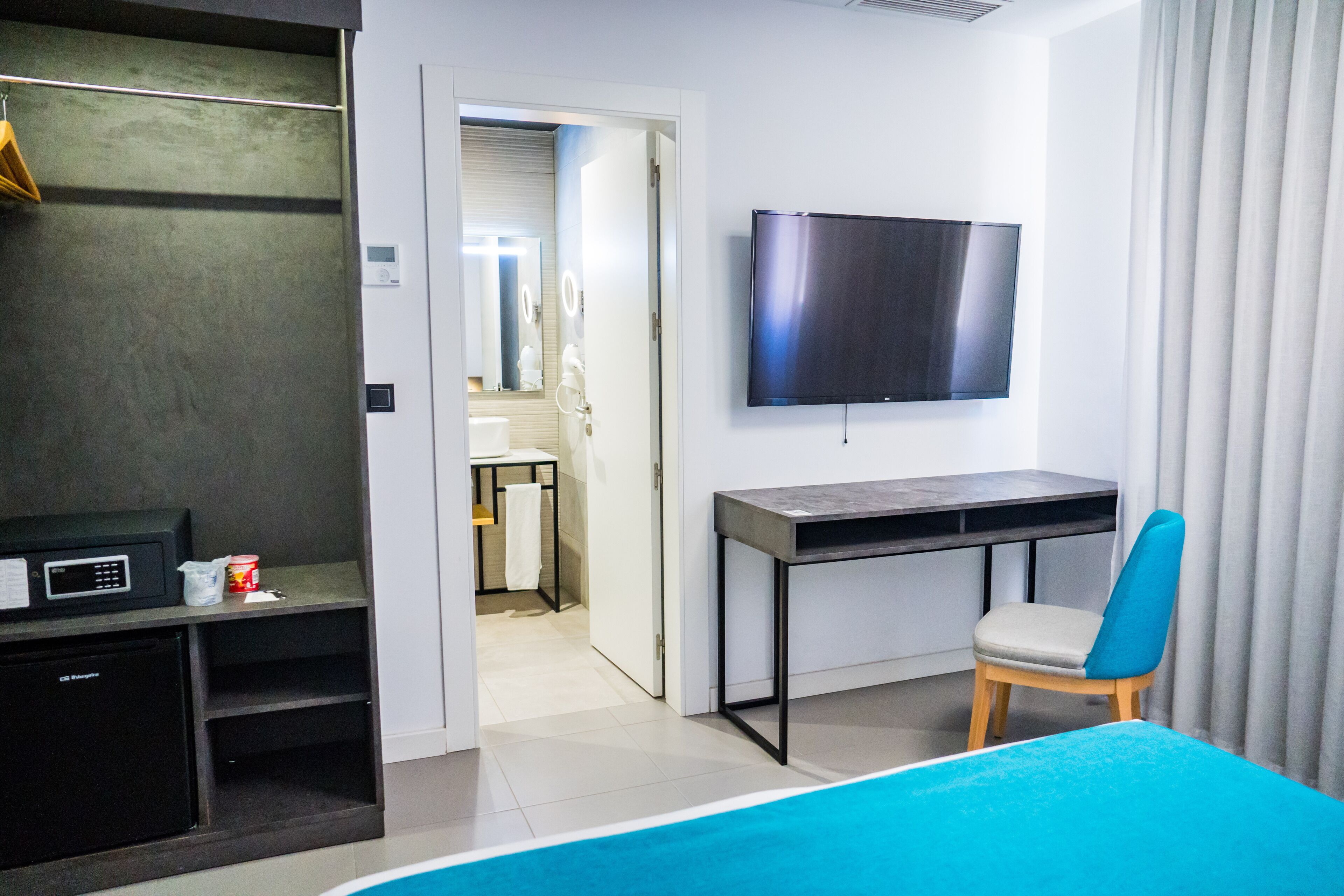 Habitación de hotel con cama, escritorio, silla, televisor, microondas y refrigerador pequeño.