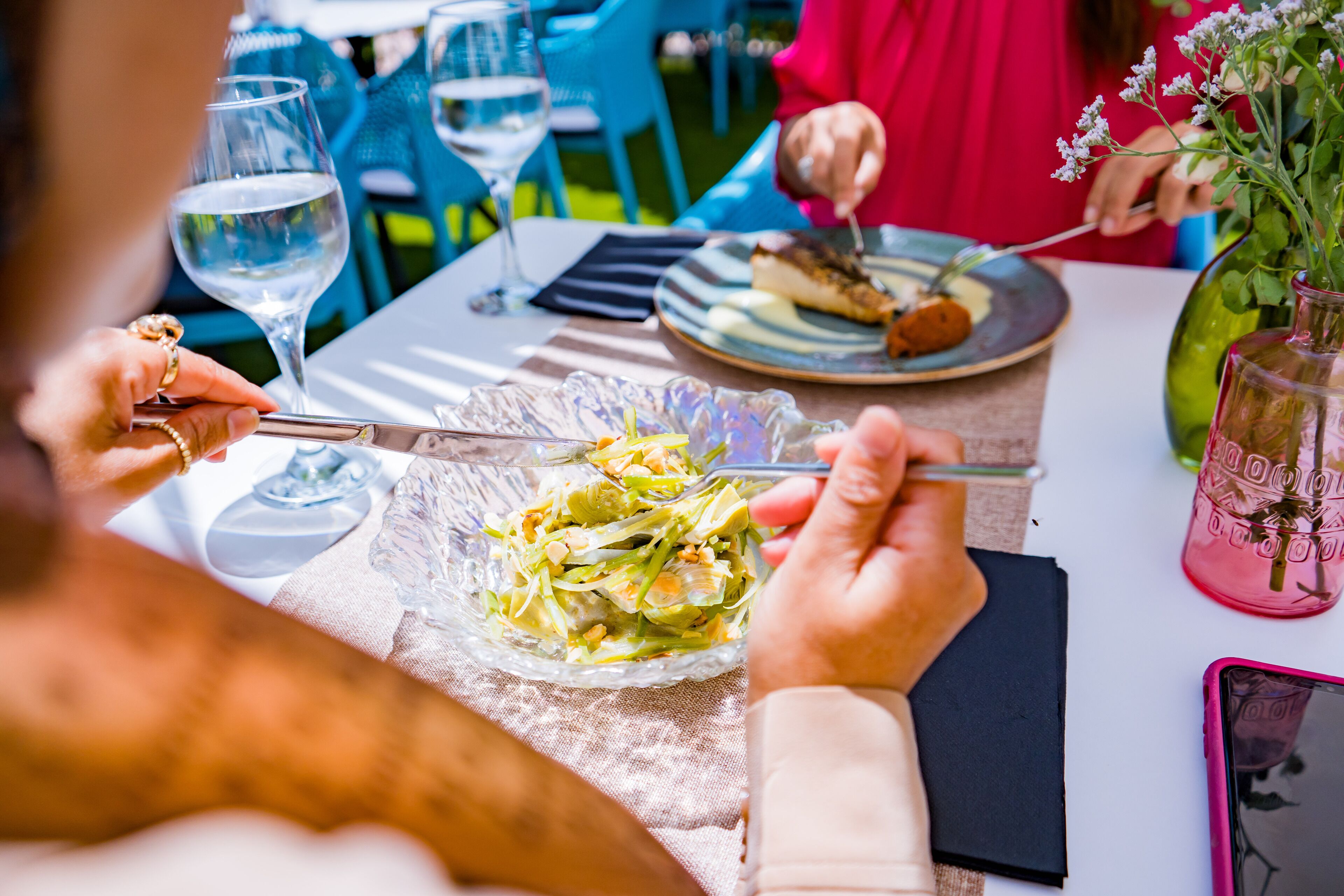 Ein Esstisch mit einem Teller Essen, einem Glas Wasser und einem Smartphone.