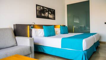 Una habitación de hotel con una cama, un sofá, una mesa y un cuadro en la pared.
