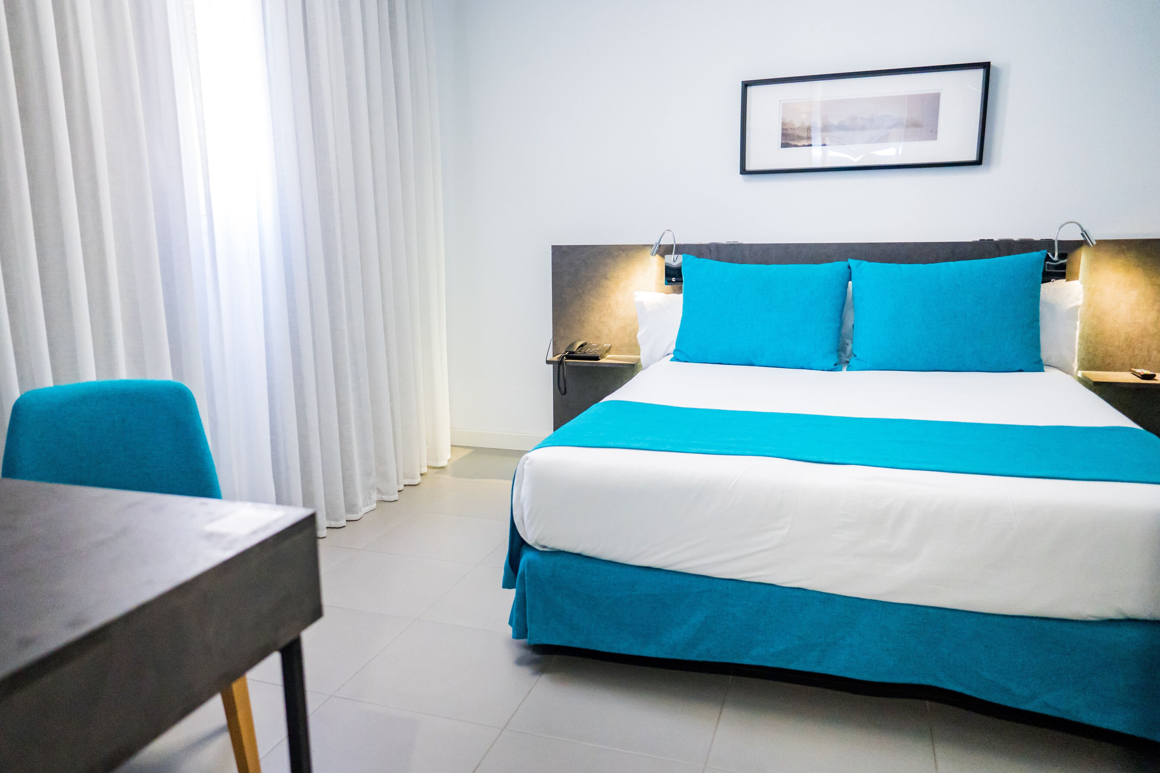 A hotel room with a bed, a desk, and a chair.