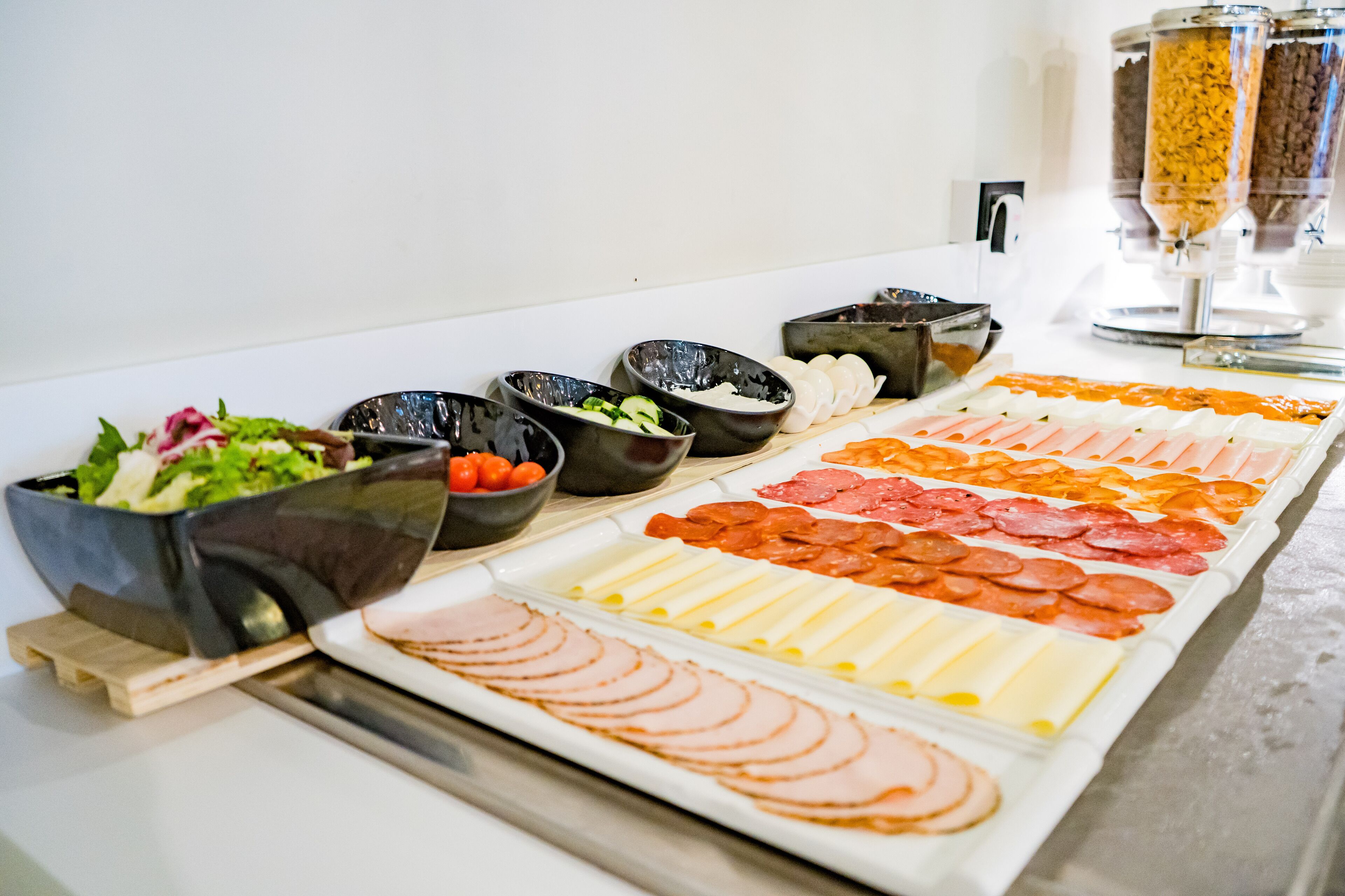 A buffet with various food items including sliced meats, cheeses, and vegetables.