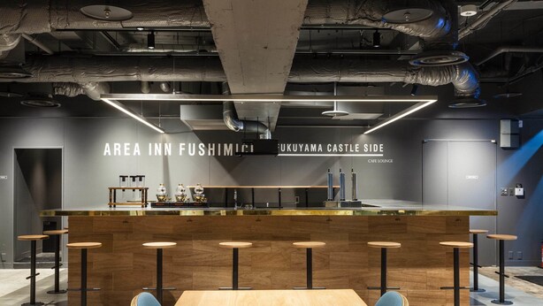 Un espace bar moderne avec un comptoir en bois, des tabourets et une grande table.