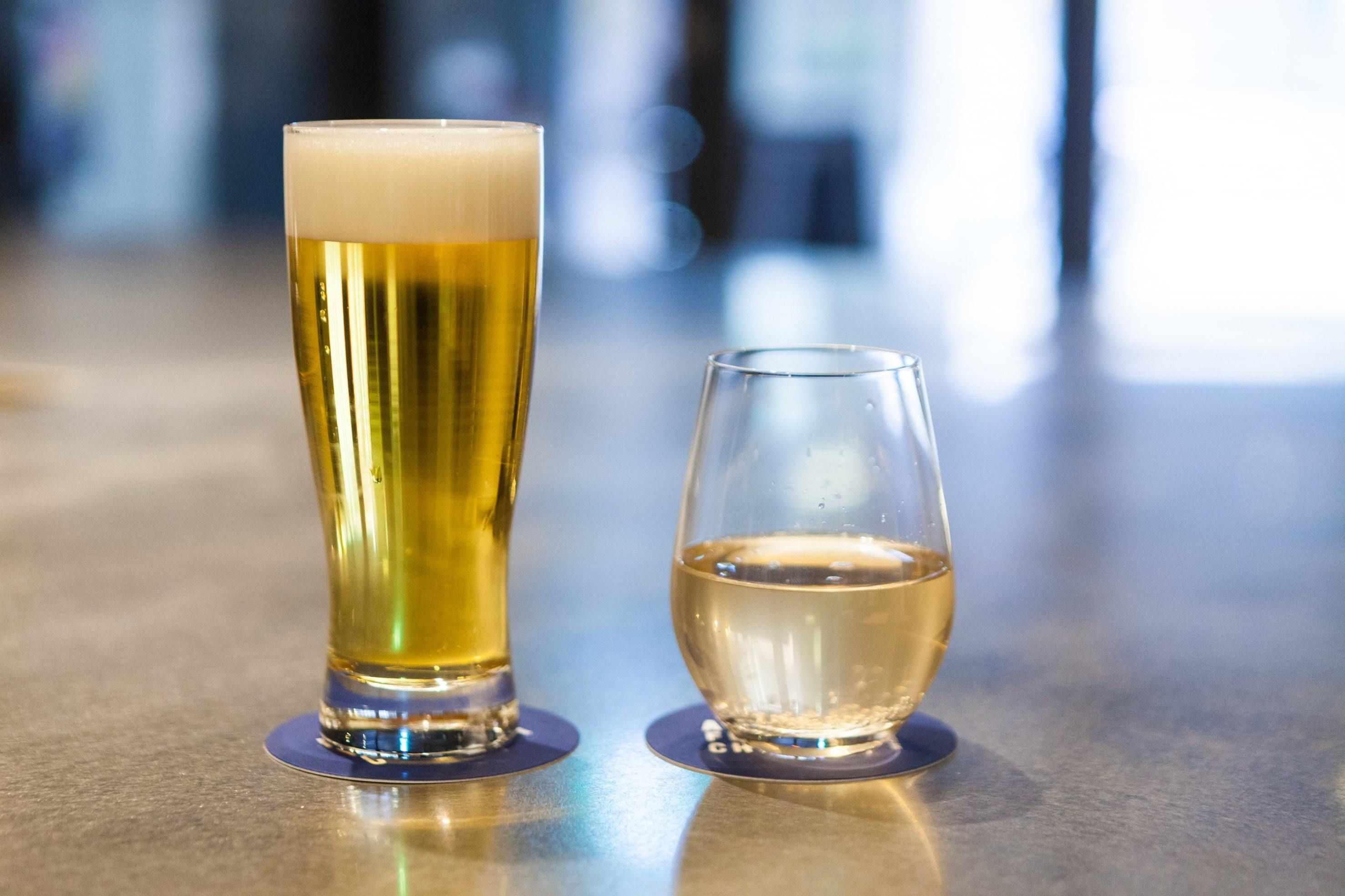 Two glasses of beer on a bar counter.