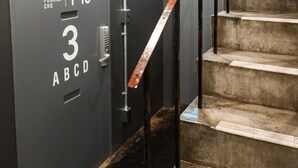 Un escalier muni d’une rampe métallique et d’une porte portant l’inscription « AREA INN FUSHIMI CHO 1-16 3 ABCD ».