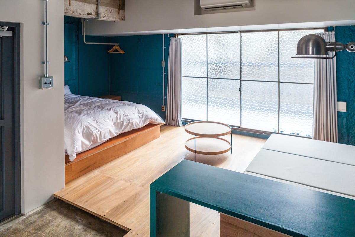 A compact bedroom with a bed, a small round table, and a window with a view of the water.