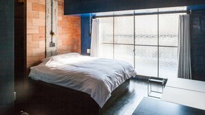Une chambre à coucher avec un lit, une fenêtre avec des rideaux, un mur en bois et une petite table.