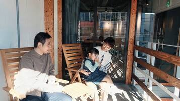 A wooden bench seating area with a glass door entrance, a small table, and a chair.