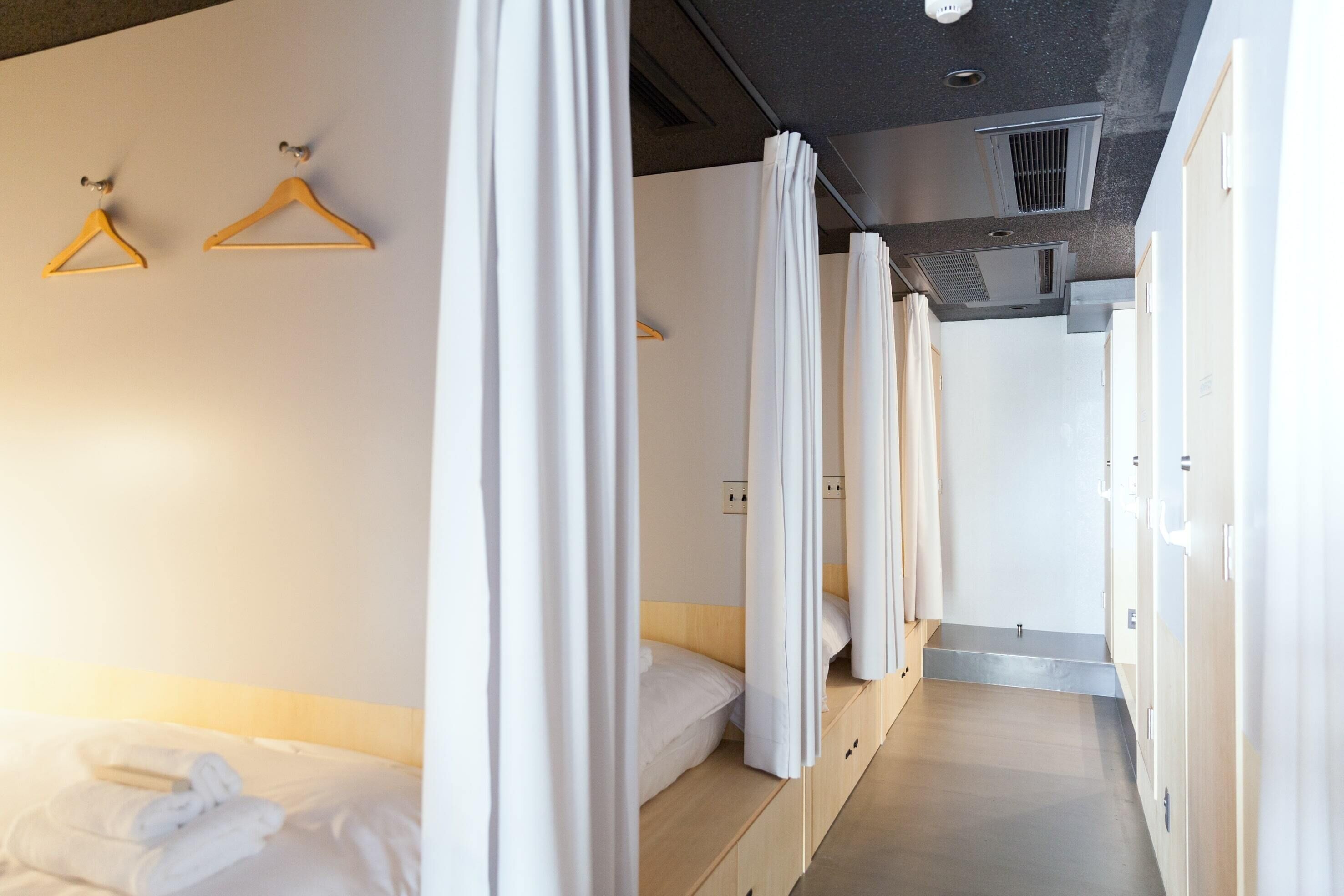 A hotel room with a bed, a wardrobe, and a shower area.