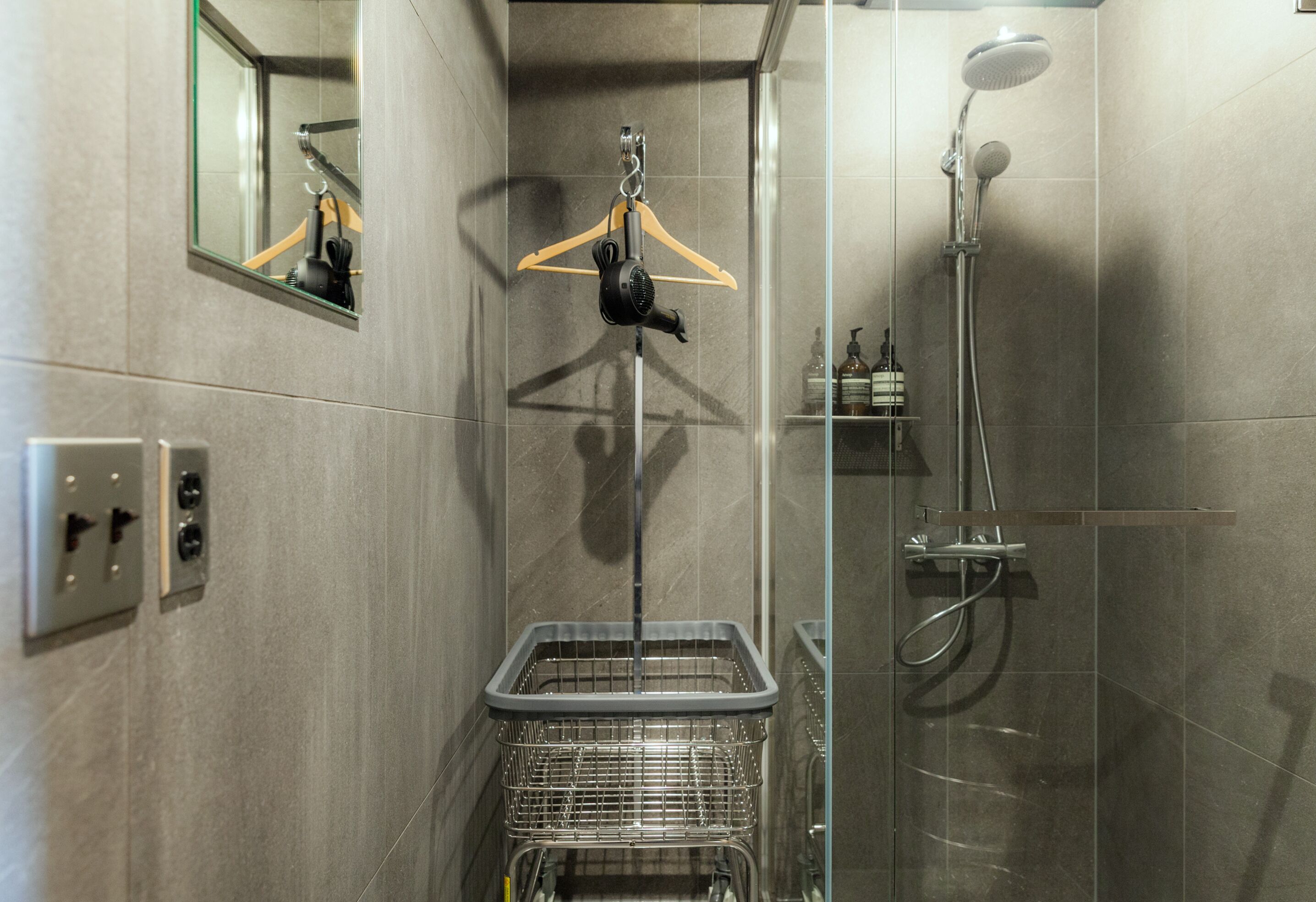 A bathroom with a shower, a mirror, a towel rack, and a metal basket.