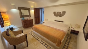 A bedroom with a bed, a dresser, a chair, a nightstand, a wall-mounted mirror, and a patterned floor. - Magnificent Views, Sleeps 2-6 Just Reduced Rates (Zihuatanejo)