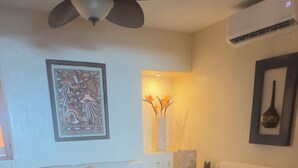 A living room with a ceiling fan, a sofa set, a coffee table, and a wall-mounted air conditioner. - Magnificent Views, Sleeps 2-6 Just Reduced Rates (Zihuatanejo)
