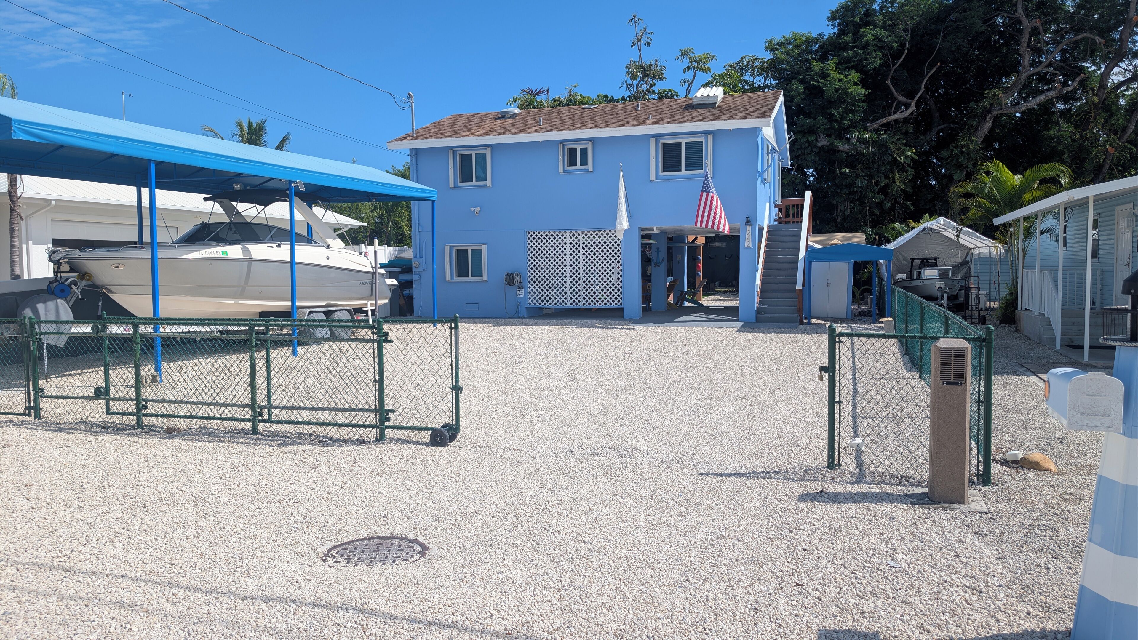 Un port de plaisance avec des bateaux amarrés, un bâtiment bleu arborant le drapeau américain et une zone abritée surmontée d’un toit bleu.