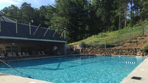 Une piscine d’un bleu éclatant, avec des chaises longues et un mur en pierre.