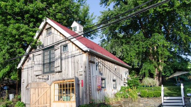 A rustic wooden building with a red roof, large windows, and a wooden door.