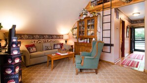 A cozy living room with a sofa, armchair, wooden coffee table, and a cabinet with glass doors.