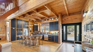 Une cuisine spacieuse dotée d’un îlot central, de planchers en bois et d’un plafond haut avec des poutres apparentes.