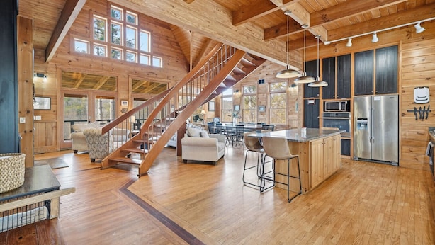 Un intérieur de chalet en bois spacieux, avec un escalier central, un coin cuisine et un espace repas.
