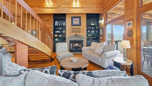 Un intérieur chaleureux avec un escalier en bois, une cheminée et un coin salon agrémenté d’une table basse.