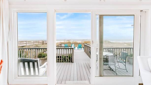 Une terrasse avec vue sur la plage, du mobilier d’extérieur et une porte vitrée donnant sur la terrasse.