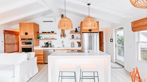 Une cuisine moderne dotée d’un îlot central, de meubles en bois et de luminaires suspendus.